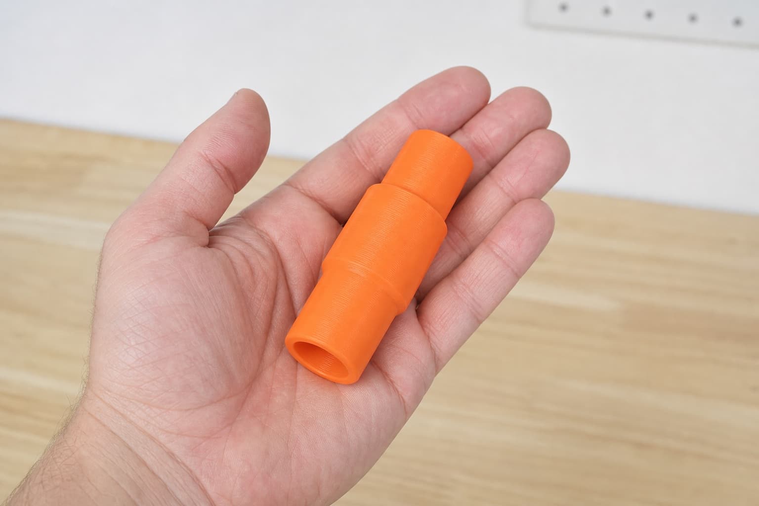 The BO6030 to Festool CT MIDI dust adapter held in one hand to show its size