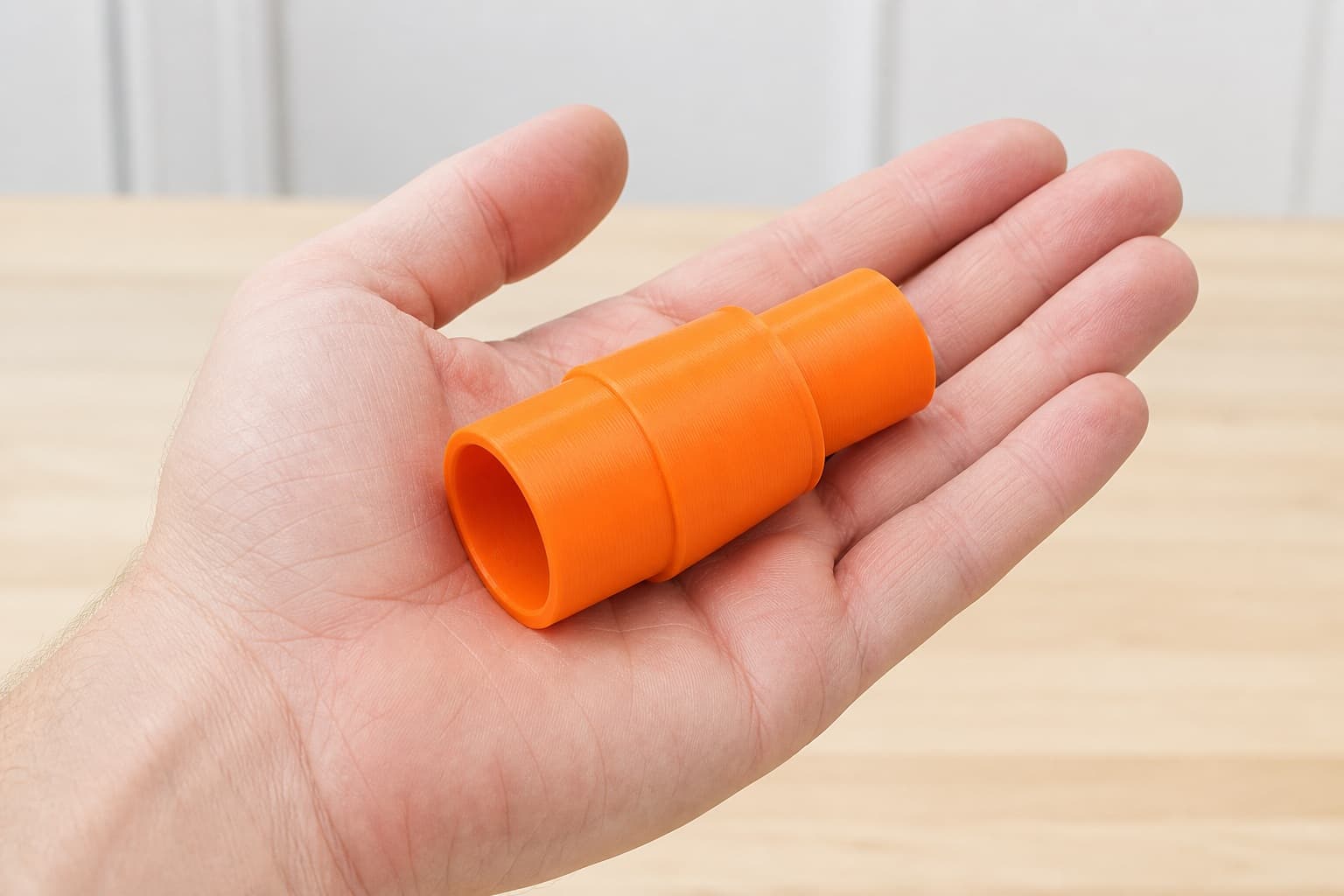 The 577017 to Bosch VAC090AH dust adapter held in one hand to show its size