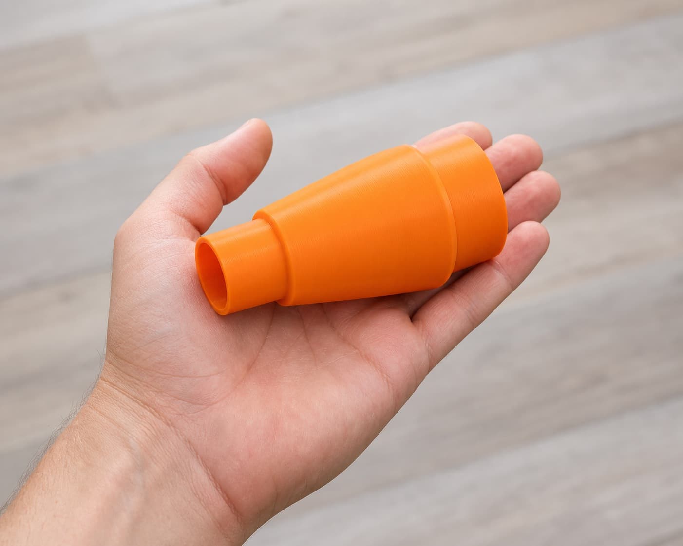 The 2723-20 to Bauer 6G Vac dust adapter held in one hand to show its size