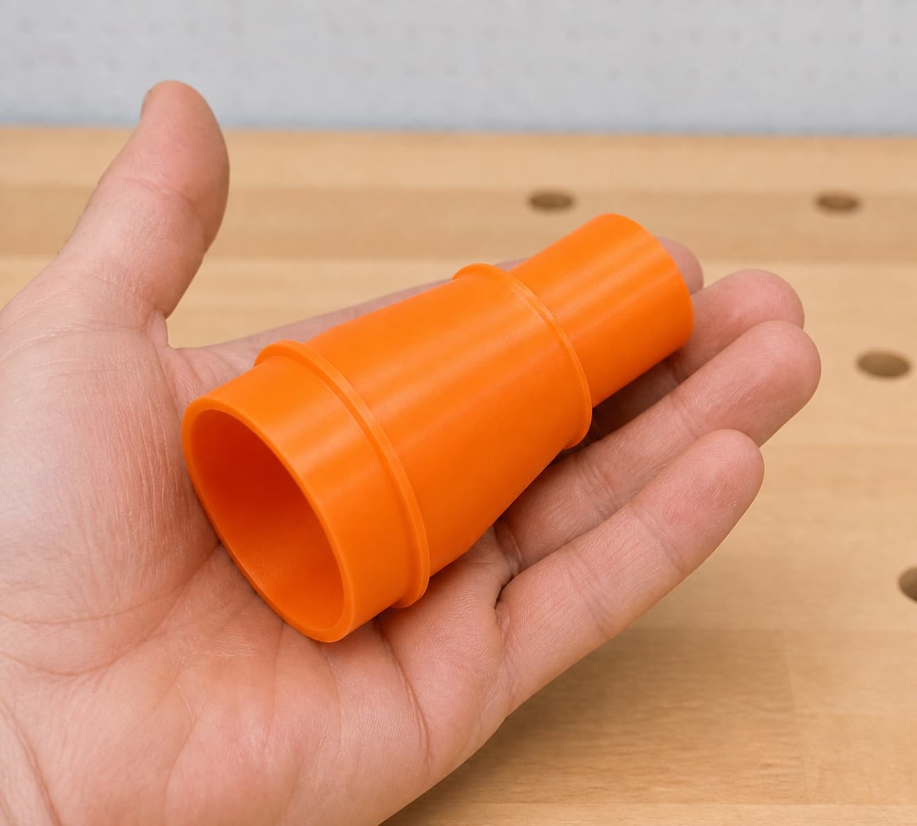 The DCW600B to M18 6G Vac dust adapter held in one hand to show its size