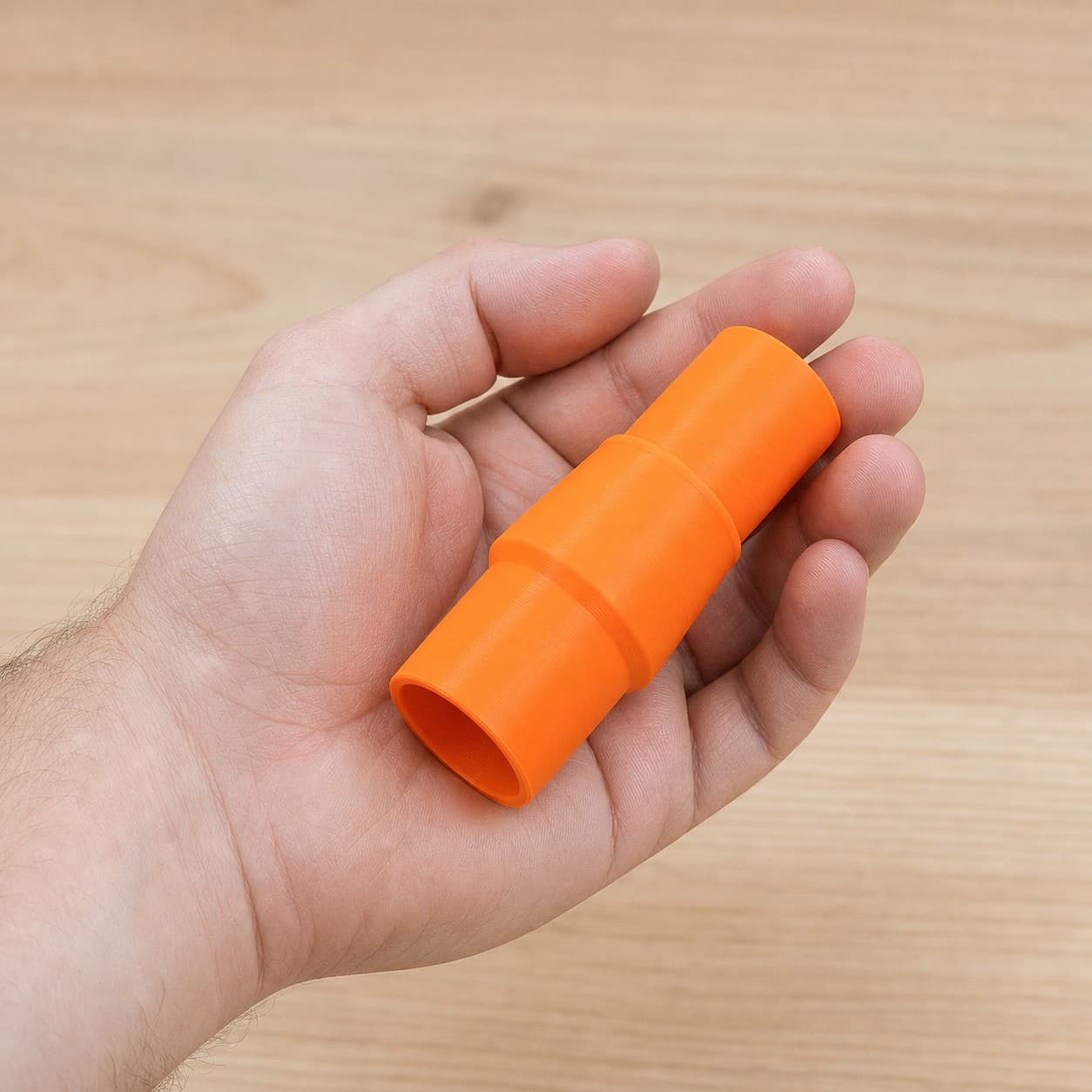 The DCS391B to 27mm Festool dust adapter held in one hand to show its size