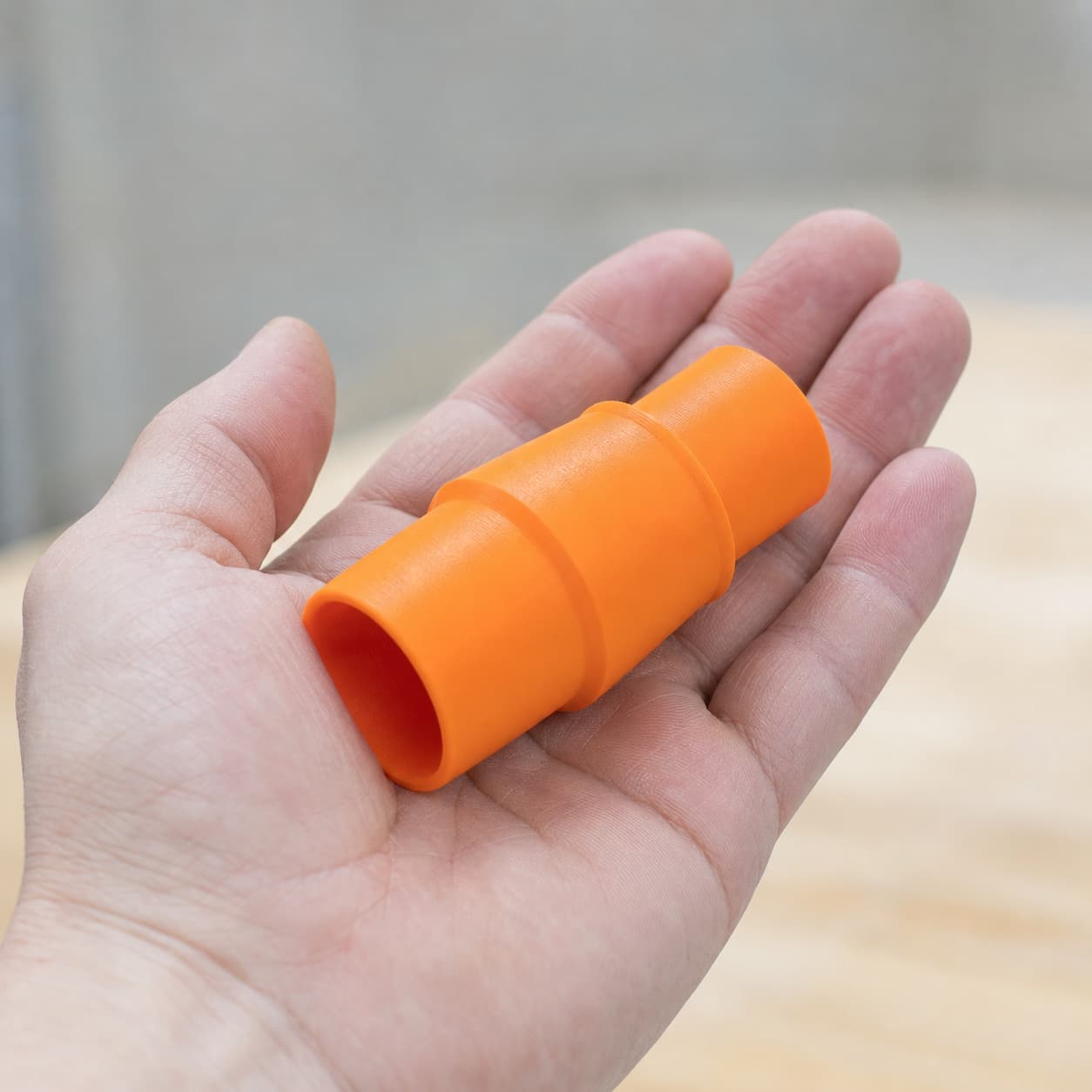 The PCL505B to Bosch VAC090AH dust adapter held in one hand to show its size
