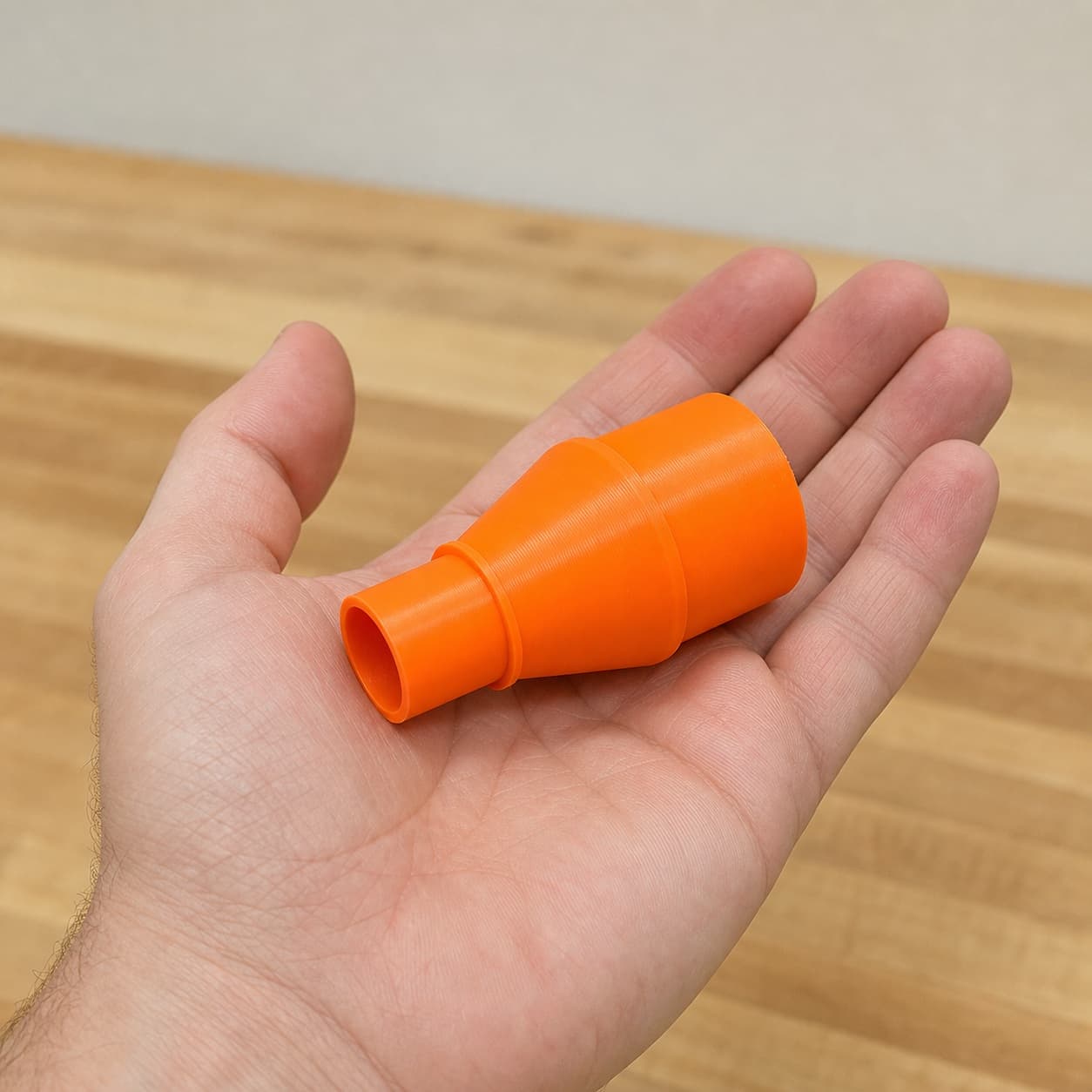 The PCC761B to M18 6G Vac dust adapter held in one hand to show its size