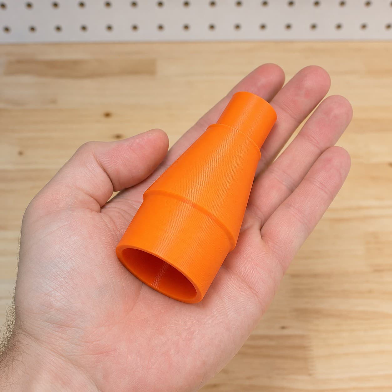 The RT0702C to Ridgid 14G NXT dust adapter held in one hand to show its size