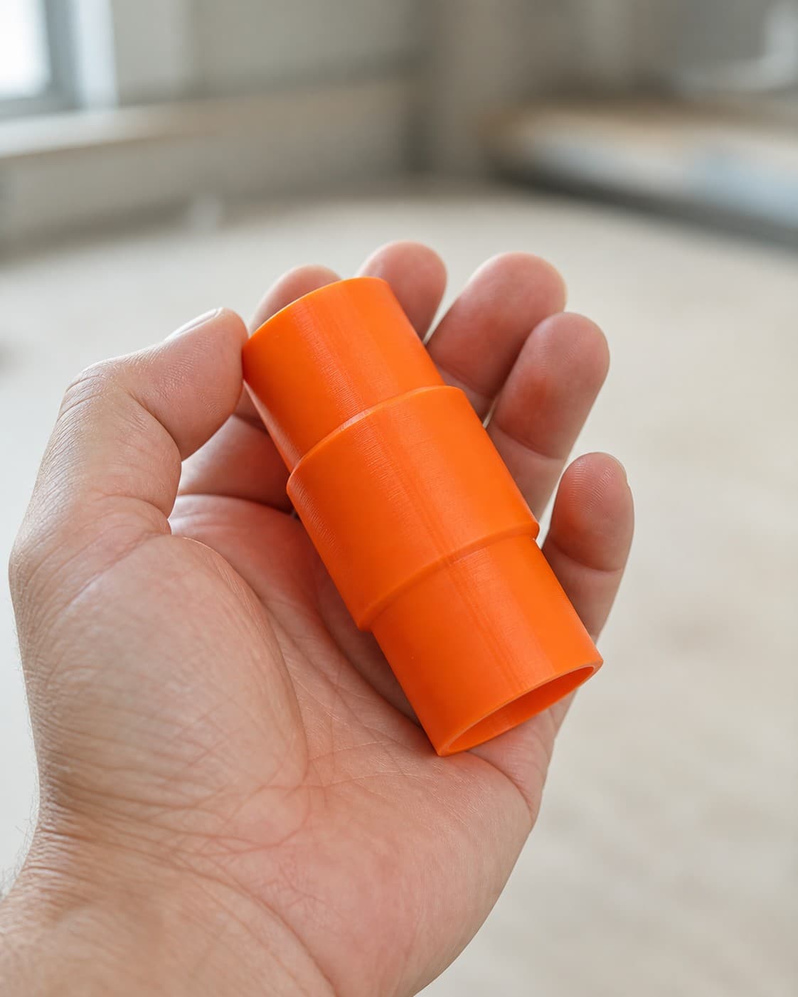 The DWS780 to DeWalt DWV012 dust adapter held in one hand to show its size
