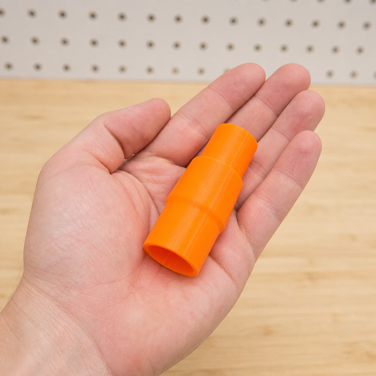 The TP-CS 18/190 Li to DeWalt DCWV201B dust adapter held in one hand to show its size