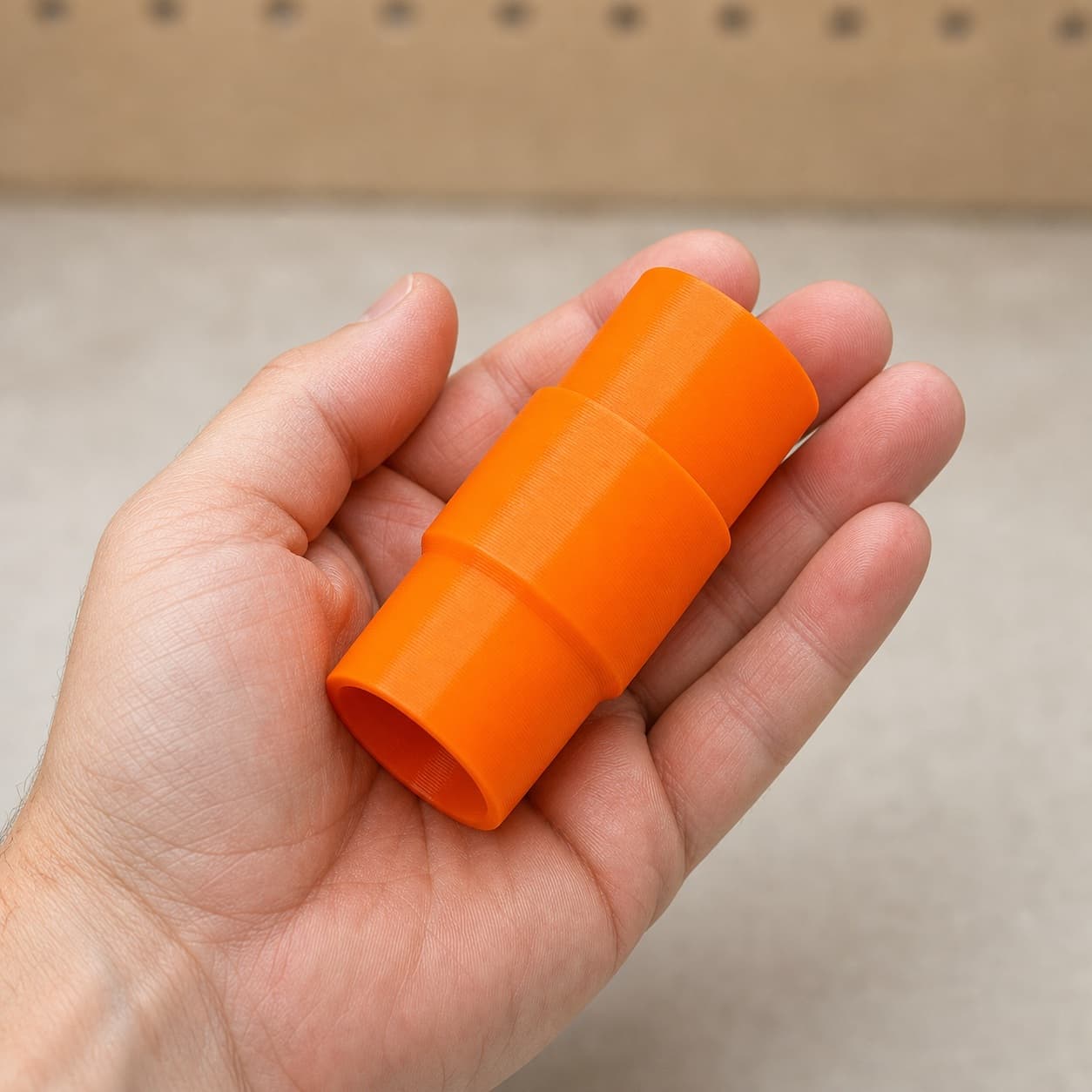 The 3386-01 to DeWalt DWV012 dust adapter held in one hand to show its size