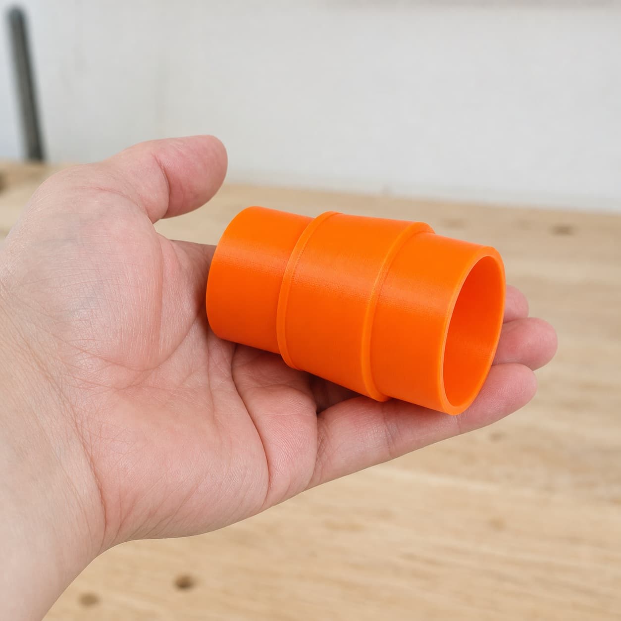 The DWE6423K to M18 6G Vac dust adapter held in one hand to show its size
