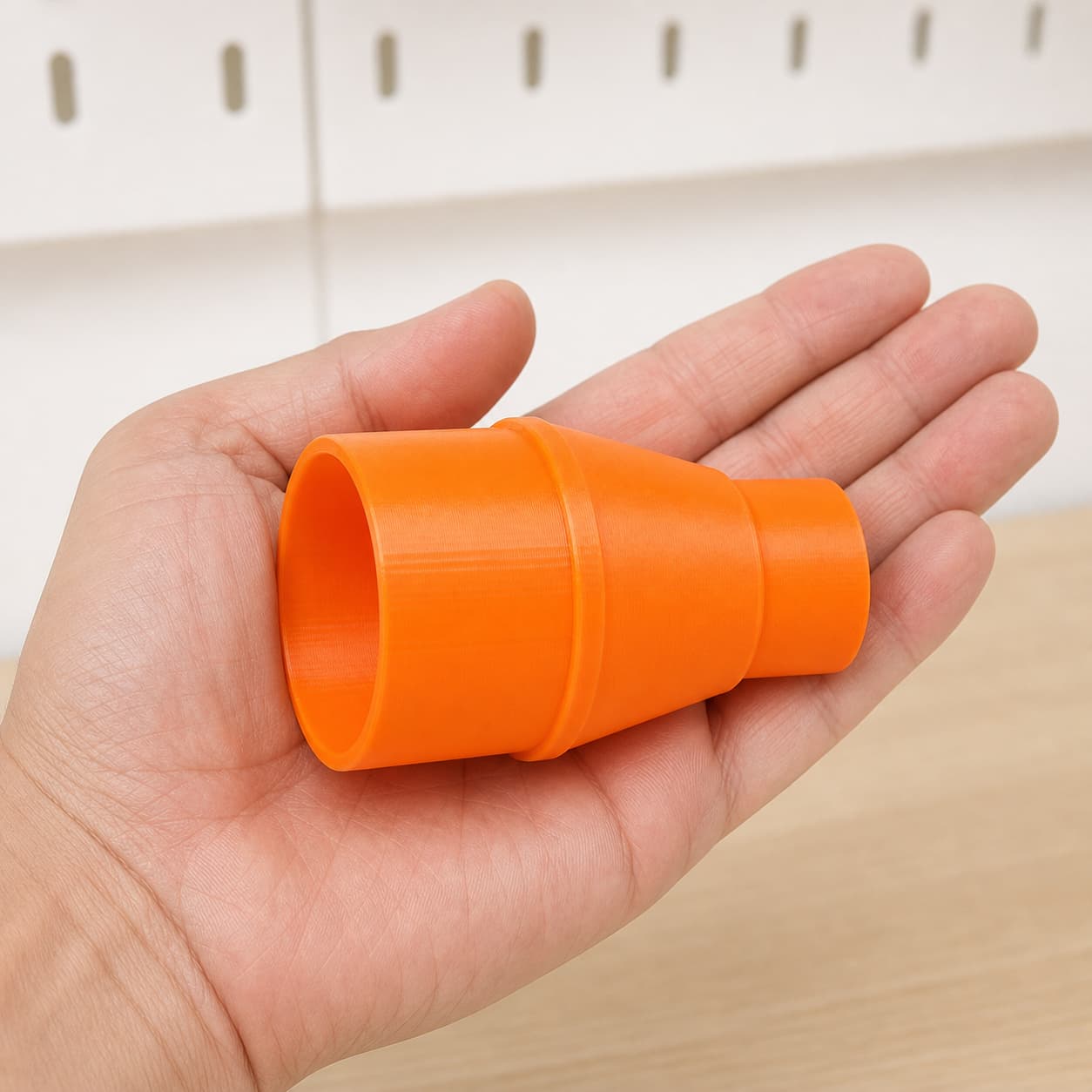 The DWE6423K to Ridgid 14G NXT dust adapter held in one hand to show its size