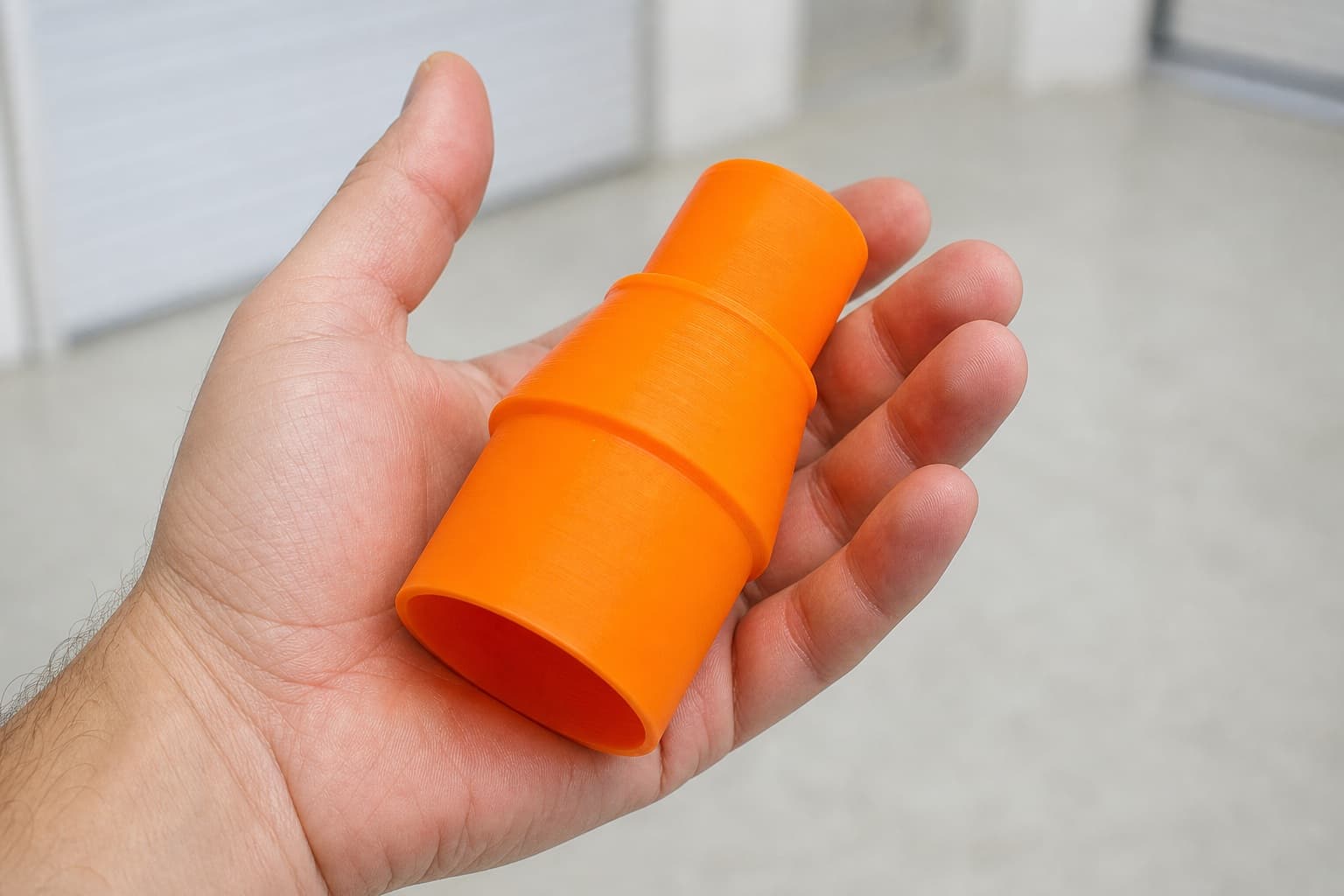 The GCM12SD to Ridgid 16G NXT dust adapter held in one hand to show its size
