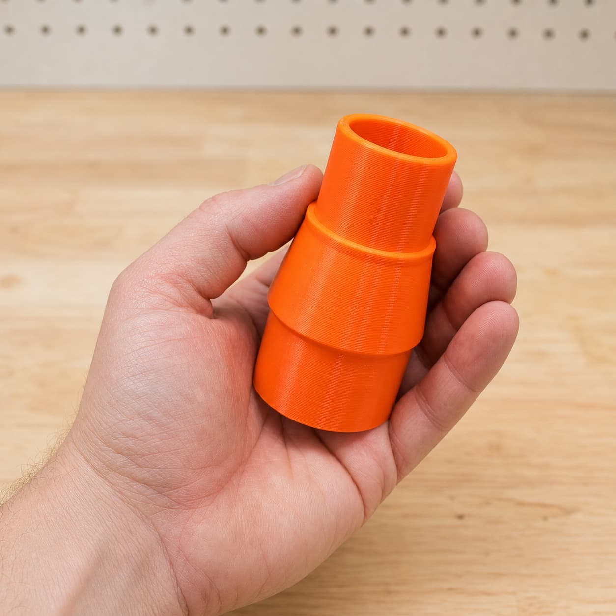 The DKP180 to Bosch GAS18V-10L dust adapter held in one hand to show its size