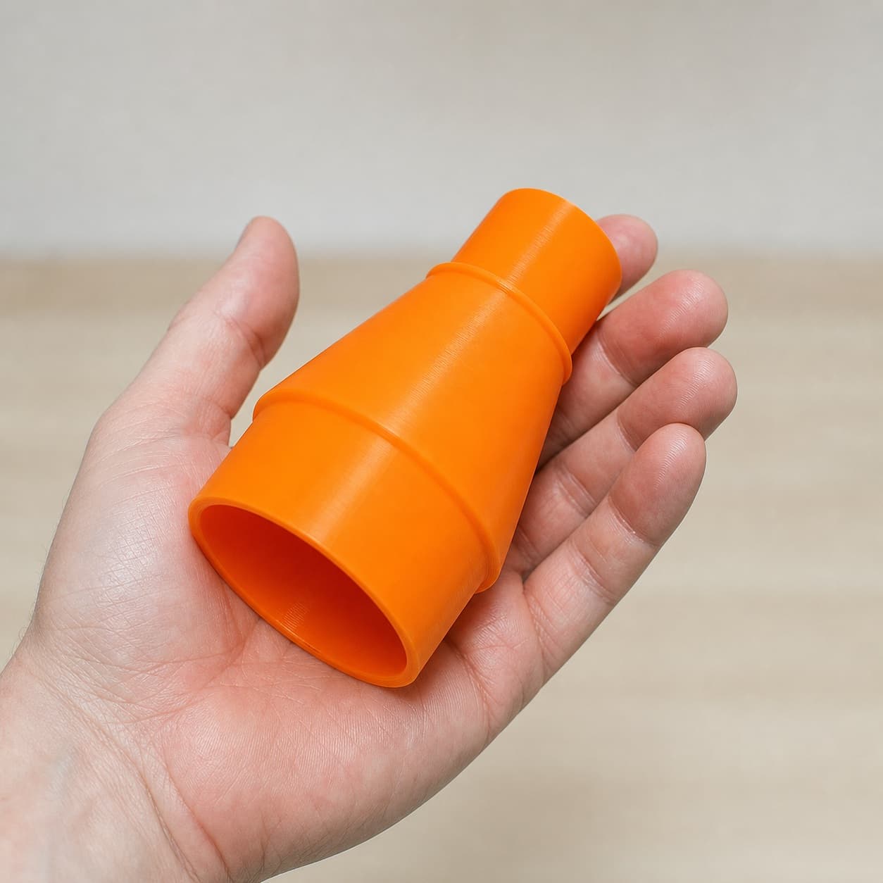 The CMXETAX to Bosch VAC090AH dust adapter held in one hand to show its size